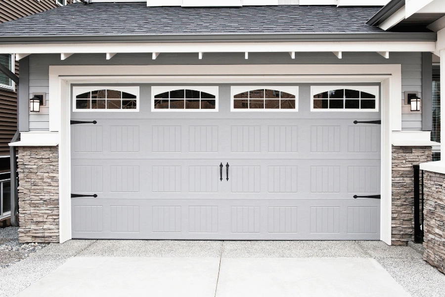 gray garage door on a home with four windows on top 